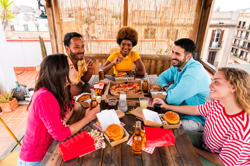 Preview: Multiethnic group of friends having dinner barbecue party on rooftop at home