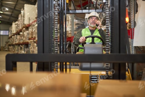 Preview: Bearded male worker driving forklift truck in warehouse