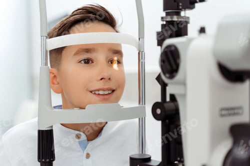 Preview: Smiling Caucasian boy receiving eye exam at clinic