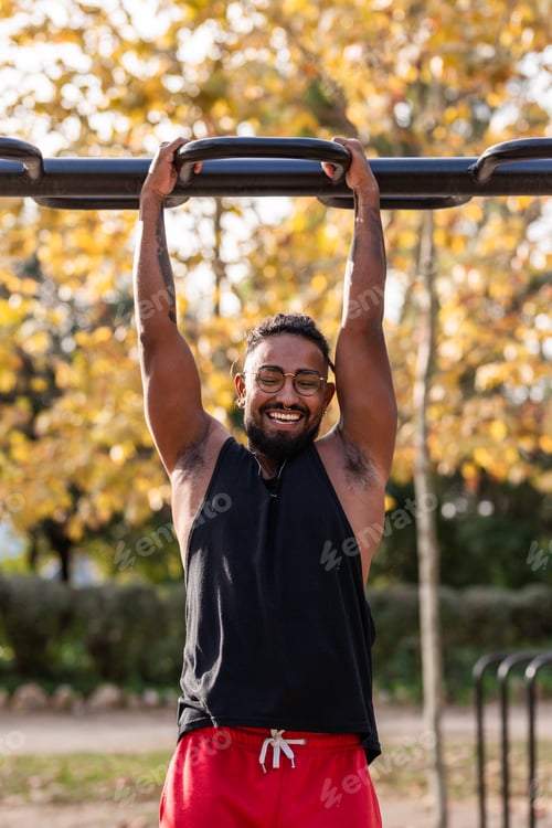 Preview: african american athlete boy does calisthenics fitness exercises on bars in park