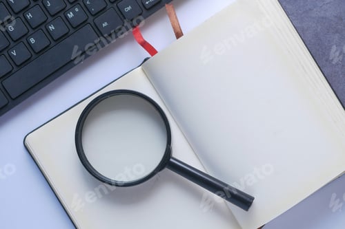 Preview: open book and magnifying glass on table.