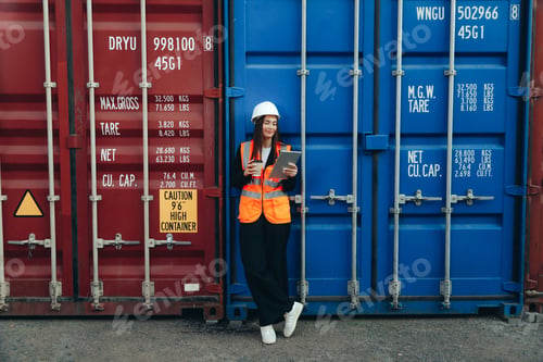 Preview: Female Engineer with Clip Folder in white helmet and vest working in container terminal port