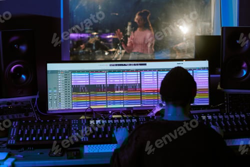 Preview: Sound Engineer Sitting at Table and Looking at Huge Monitor
