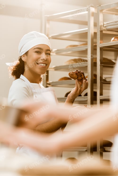 Preview: beautiful female baker with delicious croissant on baking manufacture
