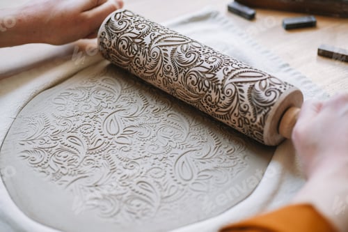 Preview: Potter's hands embossing pattern on clay plate with rolling pin