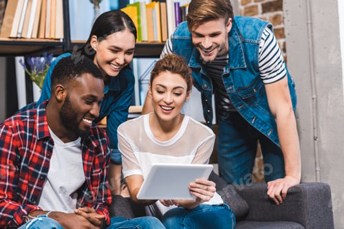 Preview: happy young multiethnic friends using digital tablet together