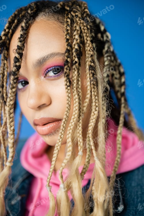 Preview: close up of african american woman with dreadlocks looking at camera on blue background, diversity