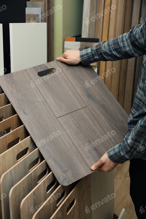 Preview: Man with sample of wooden flooring in shop, closeup