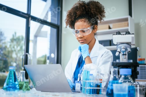Preview: An African American female scientist in a white coat and blue gloves smiles confidently, holding