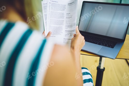 Preview: Woman with laptop reading documents while working