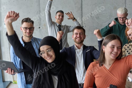 Preview: A diverse team of business professionals ecstatically celebrating their success in a modern office