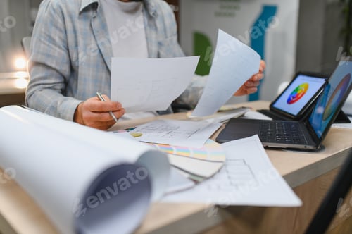 Preview: Interior designer working on blueprints and color palette