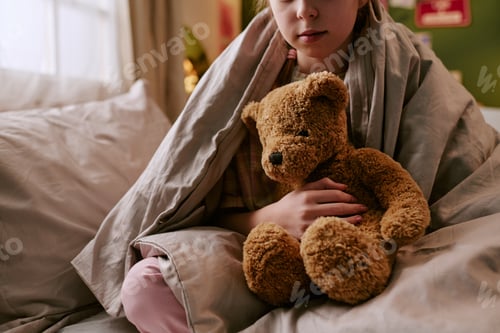 Preview: Child Sitting Indoors Holding Toy Bear under Blanket