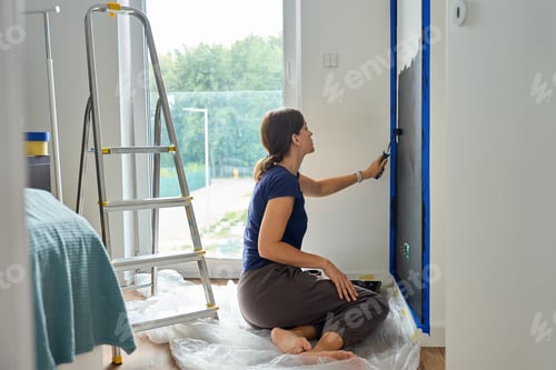 Preview: Woman painting wall with roller during home renovation