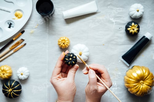 Preview: Painting black and gold pumpkins with female hands. Creative pumpkin painting ideas for Halloween