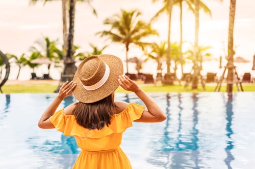 Preview: Young woman traveler enjoying the sunset by a tropical resort pool while traveling