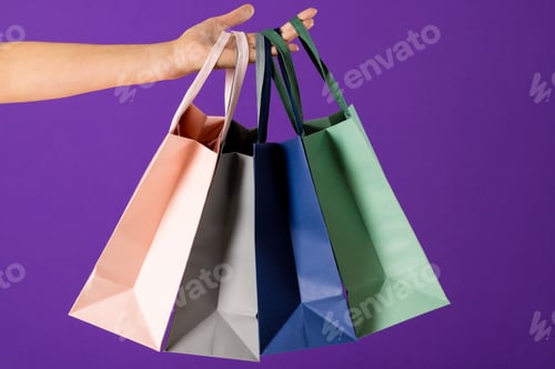 Preview: Composition of hand holding shopping bags on blue background