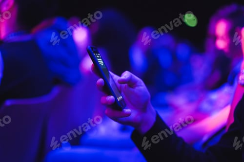 Preview: Young man using mobile phone at technology meeting event - Soft focus on front fingers