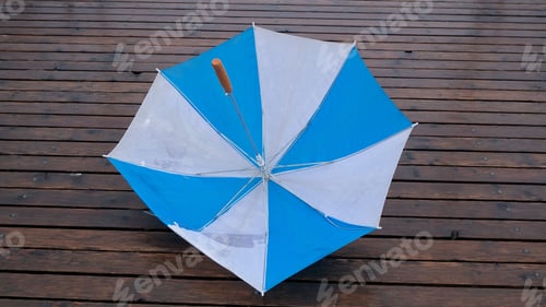 Preview: Blue and white umbrella placed on a wooden plank floor