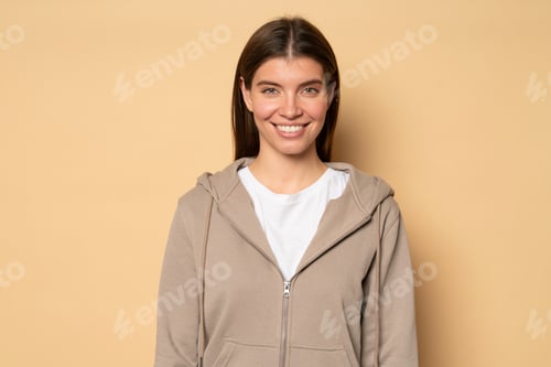 Preview: Studio portrait of young woman in casual hoodie posing, looking at camera with smile