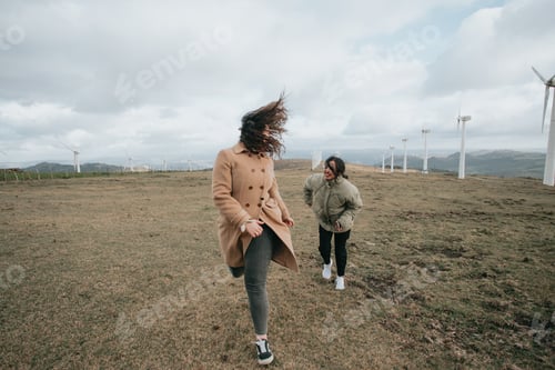 Preview: Two young women, on winter cloths during a windy day, enjoying a day while having fun running