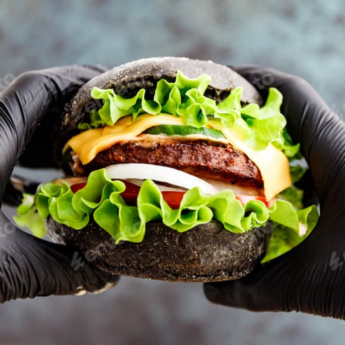 Preview: Hands in black gloves hold a big black burger