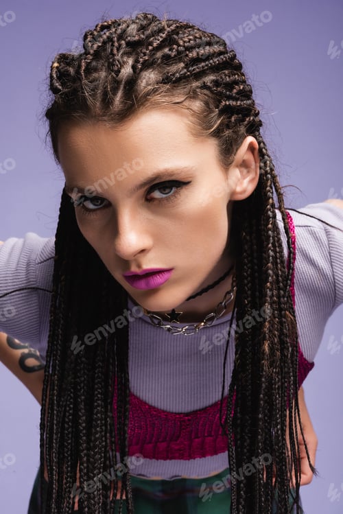 Preview: portrait of trendy woman with dreadlocks and makeup looking at camera isolated on purple