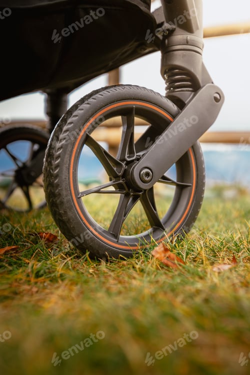 Preview: Detail on outdoor stroller wheel on green mountain meadow in winter