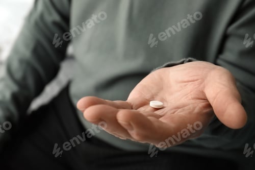 Preview: Senior man holding pill in his hand, closeup
