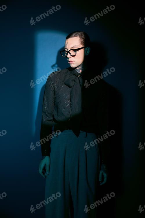 Preview: Striking elegance of a young man in fashionable attire against a bold blue backdrop