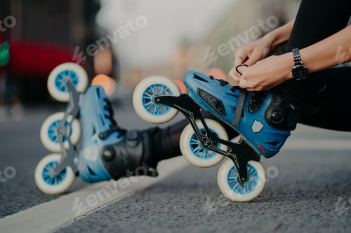 Preview: faceless woman puts on rollerskates rides on road poses against urban background