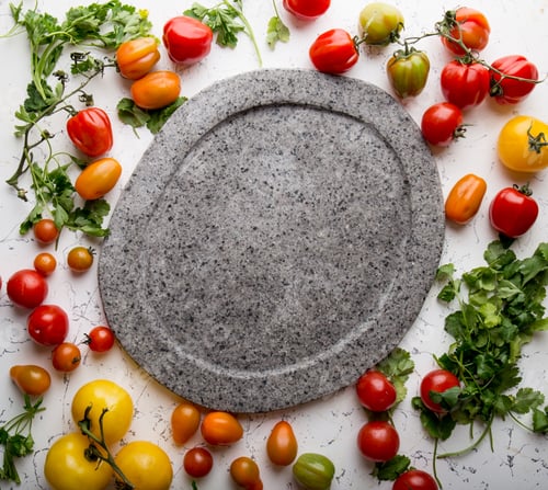 Preview: Gray empty stone plate and fresh cooking ingredients - green. red, yellow orange tomatoes and herbs