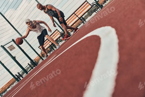 Preview: Playing basketball. Two young men in sports clothing playing basketball while spending time outdoors