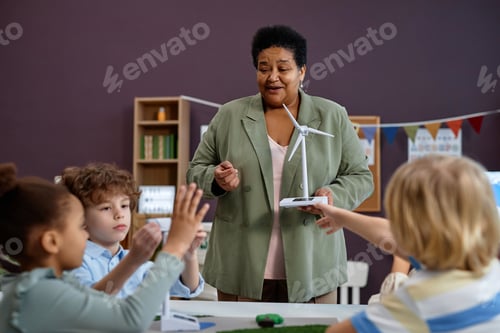 Visualização: Mulher negra segurando modelo de turbina eólica ensinando grupo de crianças na pré-escola