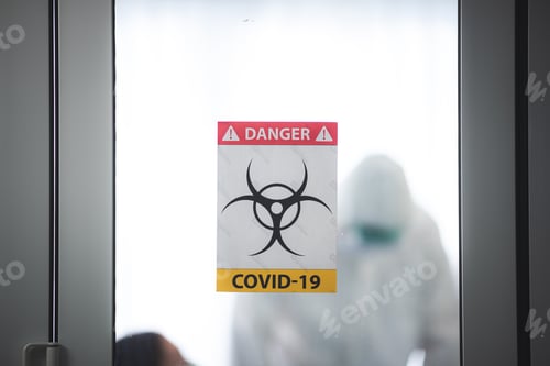 Preview: Hazmat Suit and COVID-19 Warning Sign on Glass