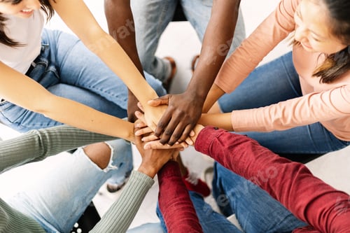 Preview: Multiethnic young people putting their hands together showing unity and teamwork