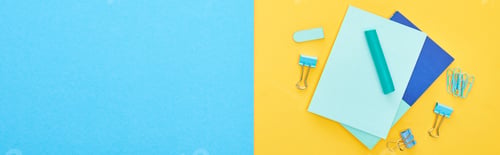 Preview: Panoramic shot of different blue stationery with sheets of paper on bicolor background