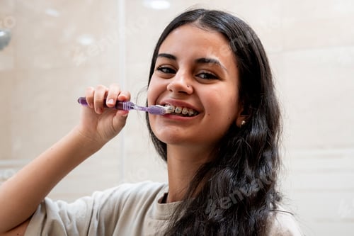 Preview: Dental care: young girl with braces brushing her teeth