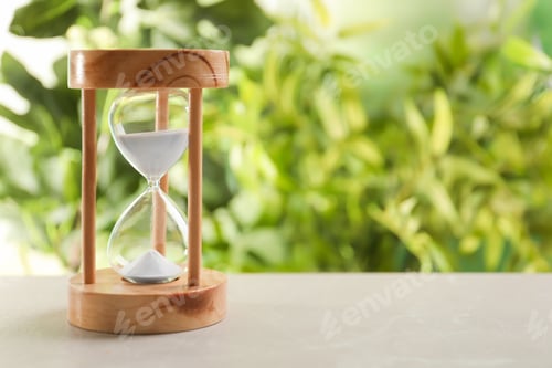 Preview: Hourglass with flowing sand on table against blurred background. Time management