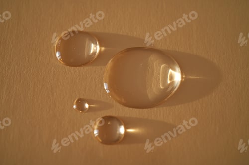 Preview: Beautiful volumetric drops of cosmetic product on a beige background.