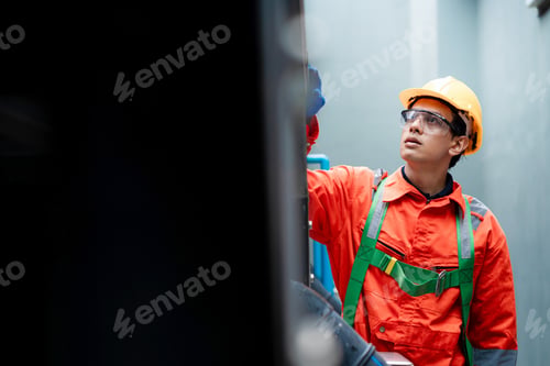 Preview: A man in a red and green safety suit is working on a machine