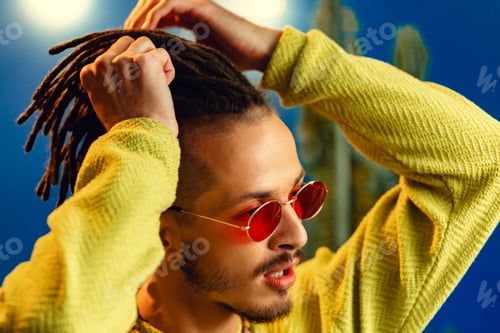 Preview: Portrait of a positive handsome caucasian guy with dreadlocks against blue background