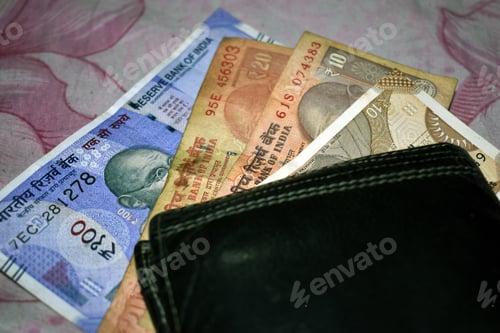 Preview: Top view closeup of several Indian rupee banknotes placed on the table along with a leather wallet