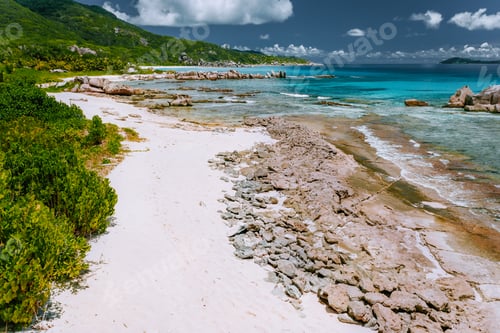 Preview: Old coral reef in the white sand beach on secluded beach of grand anse, La Digue, Seychelles. Aerial