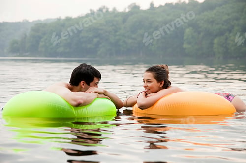 Preview: Young couple on inflatable rings on lake