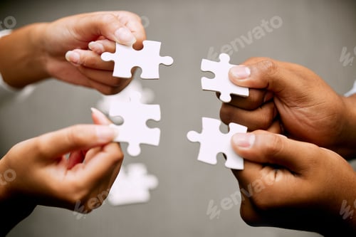 Preview: Closeup shot of a group of unrecognizable businesspeople holding puzzle pieces together