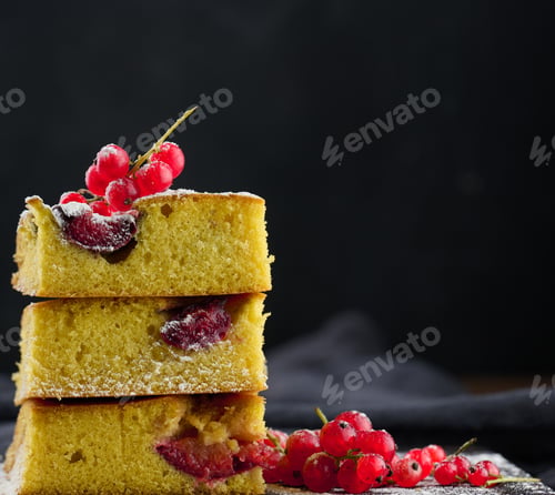 Preview: A stack of square slices of baked plum biscuit cake, sprinkled with powdered sugar on top