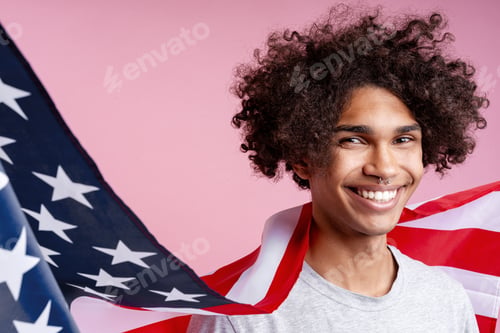Preview: Happy African American man holding american flag looking away isolated on pink background