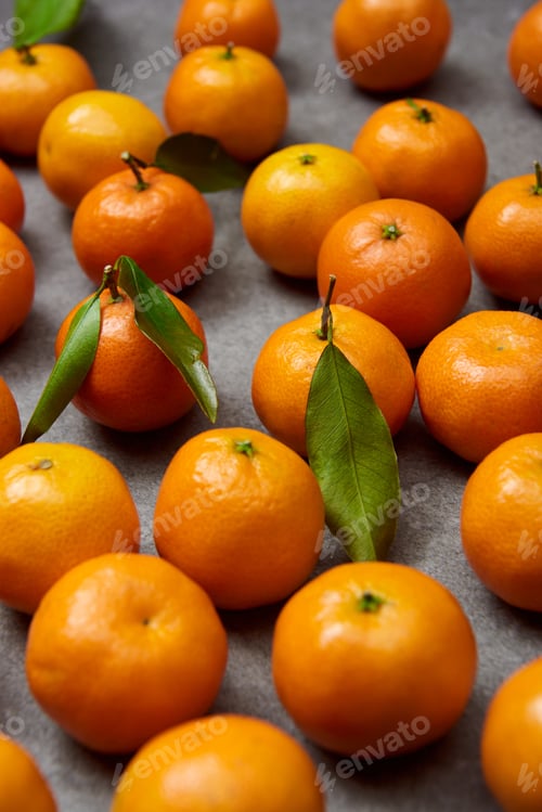 Preview: selective focus of sweet tangerines with green leaves on grey table