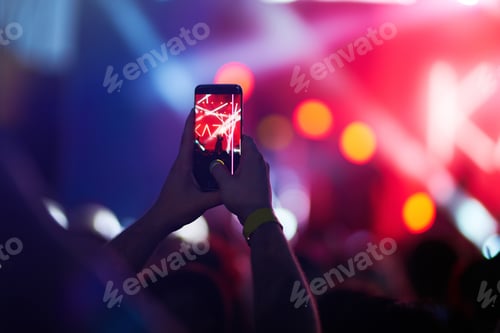 Preview: Hand with phone records live music festival. People taking photographs with phone during concert.